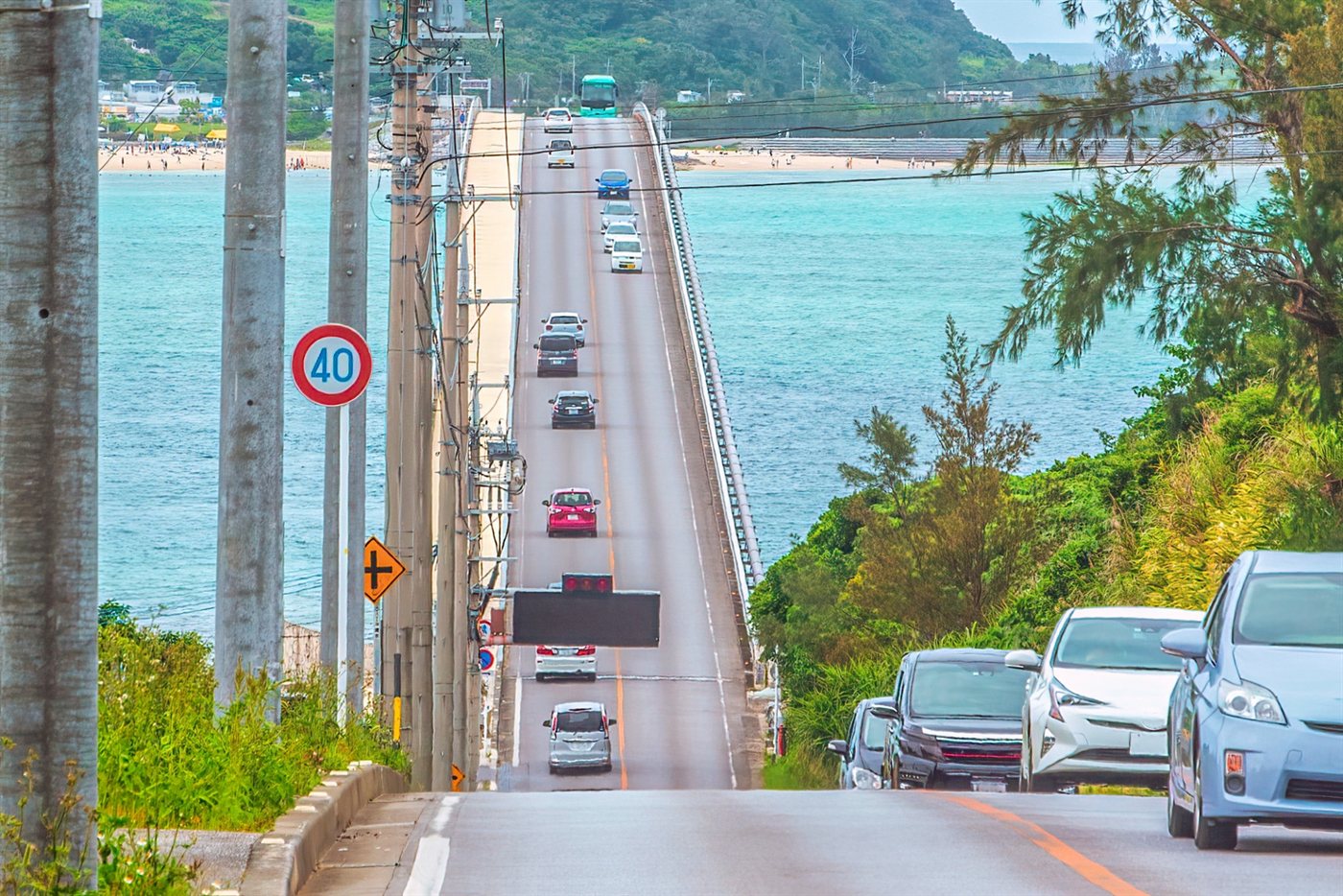 沖縄県道247号線（名護市済井出）。海沿いを走る道路と行き交う車